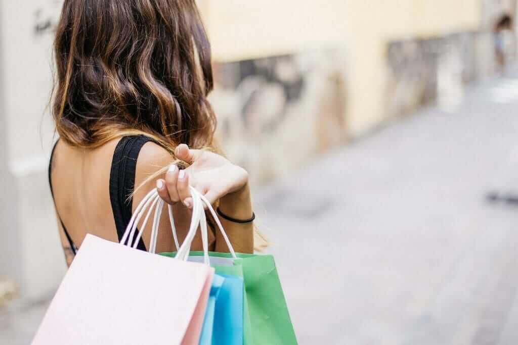 women holding multiple shopping bags after spending cash quickly