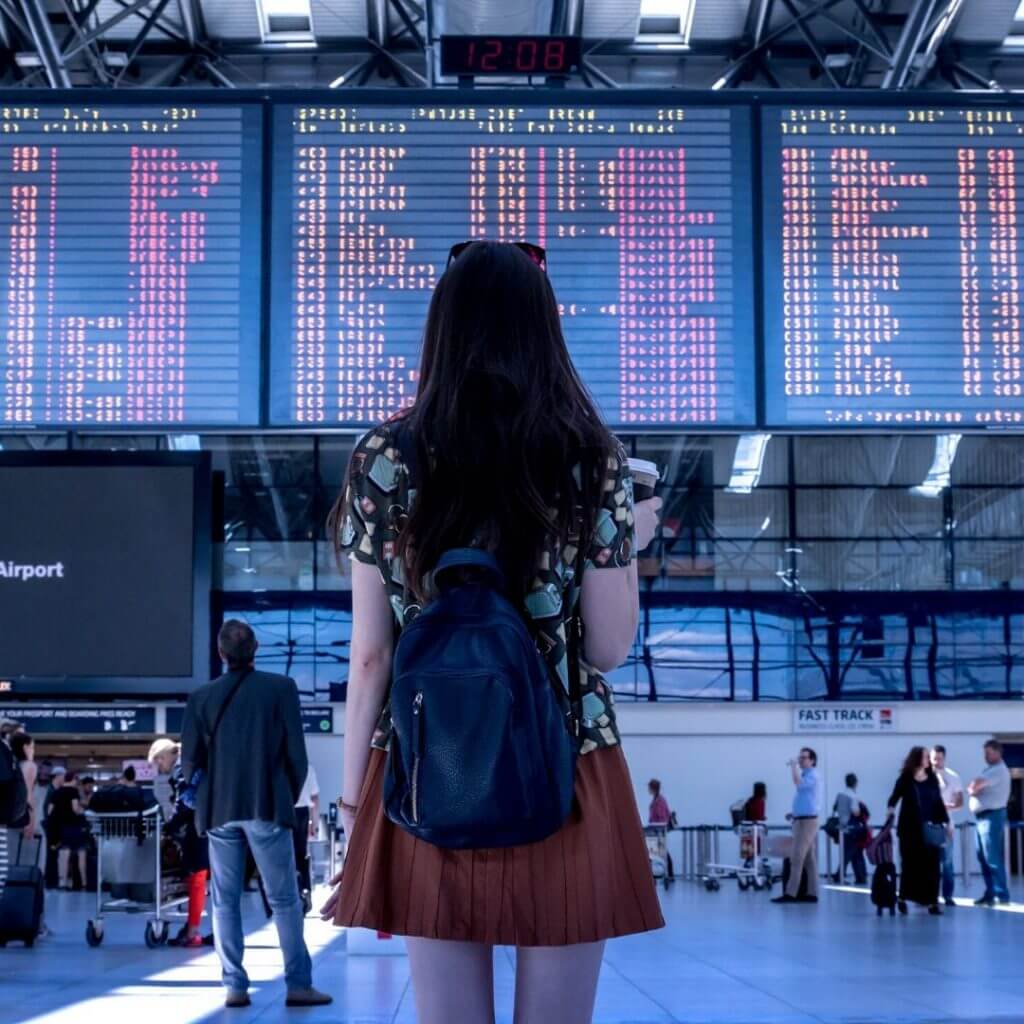 woman waiting looking at board with times on it 