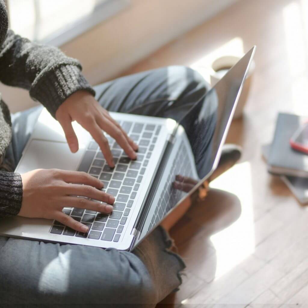 person sat on floor using computer Looking For Holiday Deals To Save Money