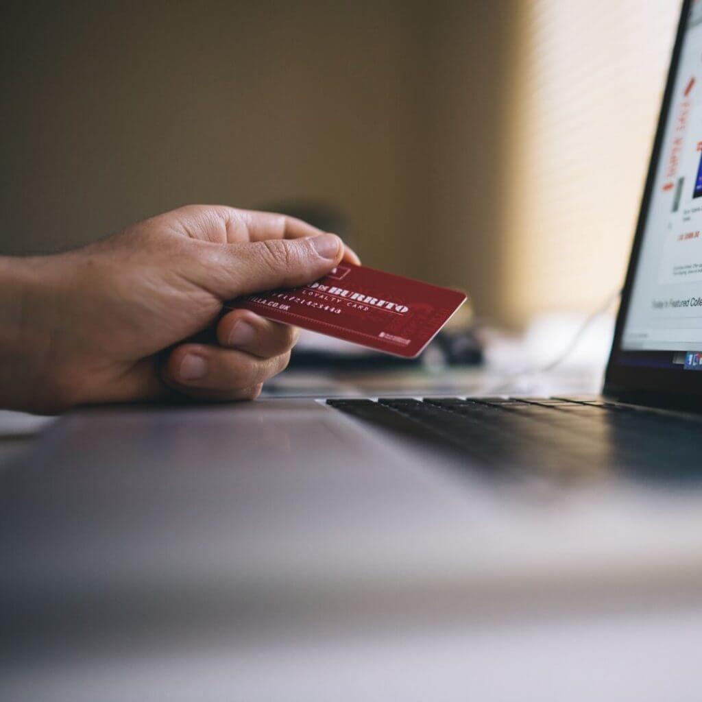 person holding card next to computer