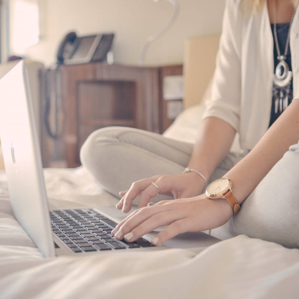 Make money from your own home - woman sat on bed on computer